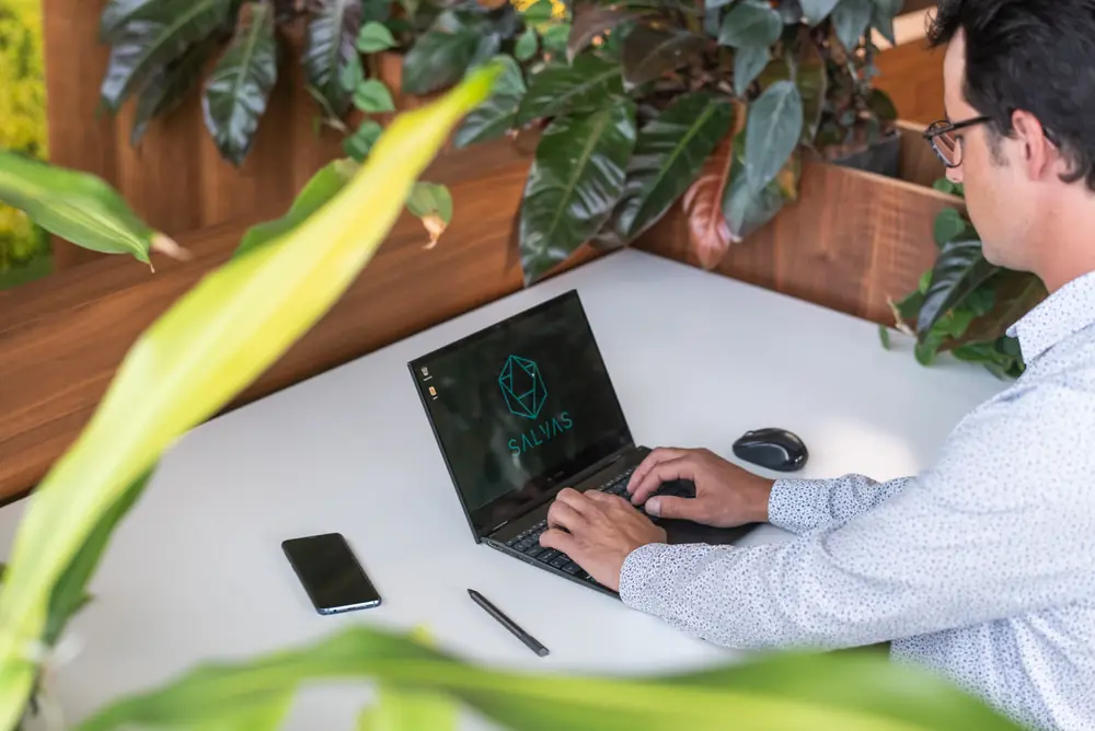 Stephan Gasser schreibt am Laptop einen Gesprächsleitfaden für die Telefonakquise, daneben Smartphone und Stift